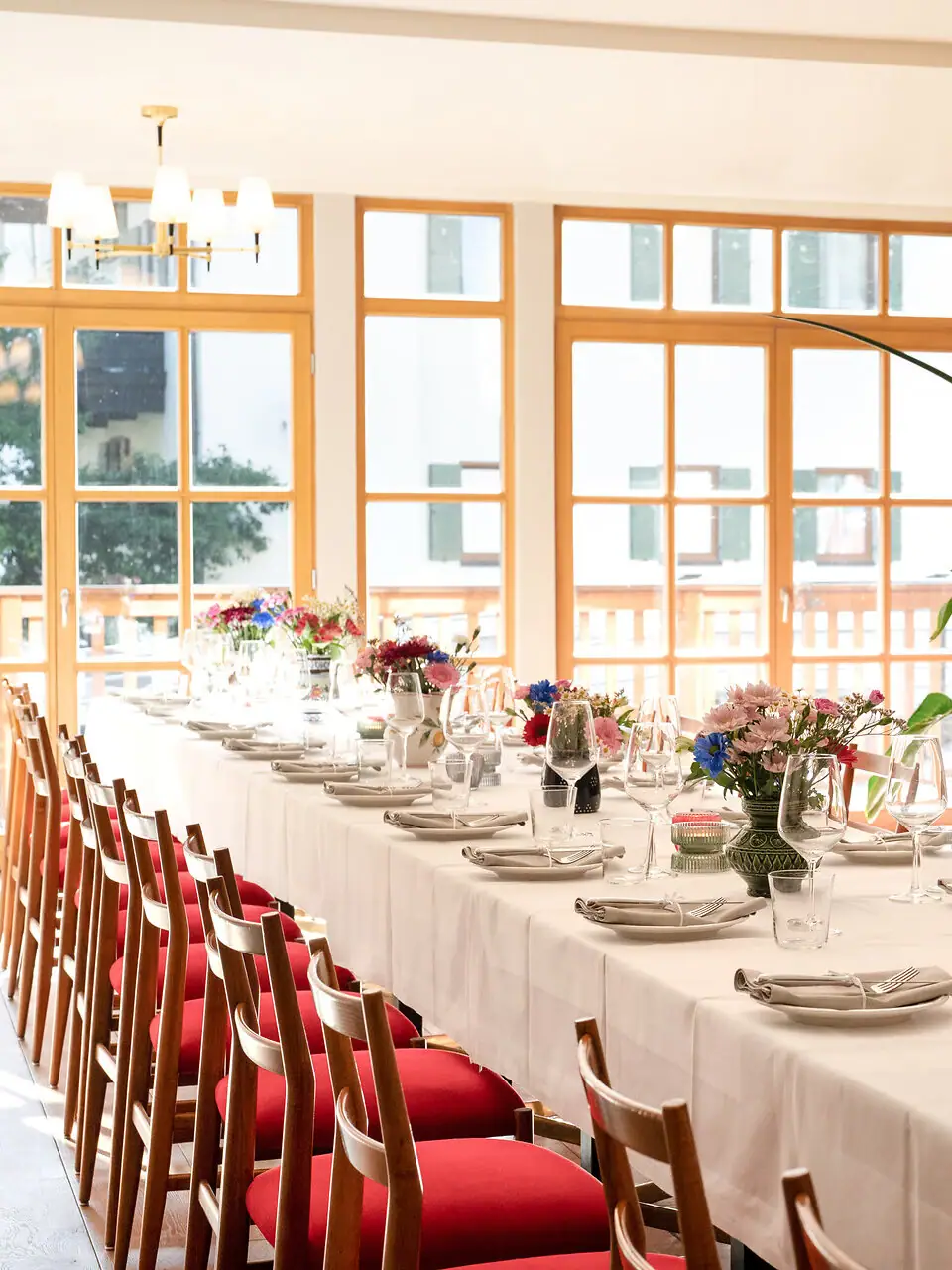 Tavolo lungo con tovaglia bianca e fiori.