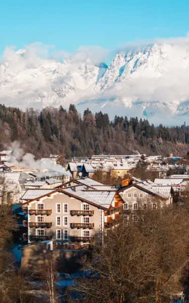 Villaggio di montagna innevato con alberi e cielo nuvoloso.