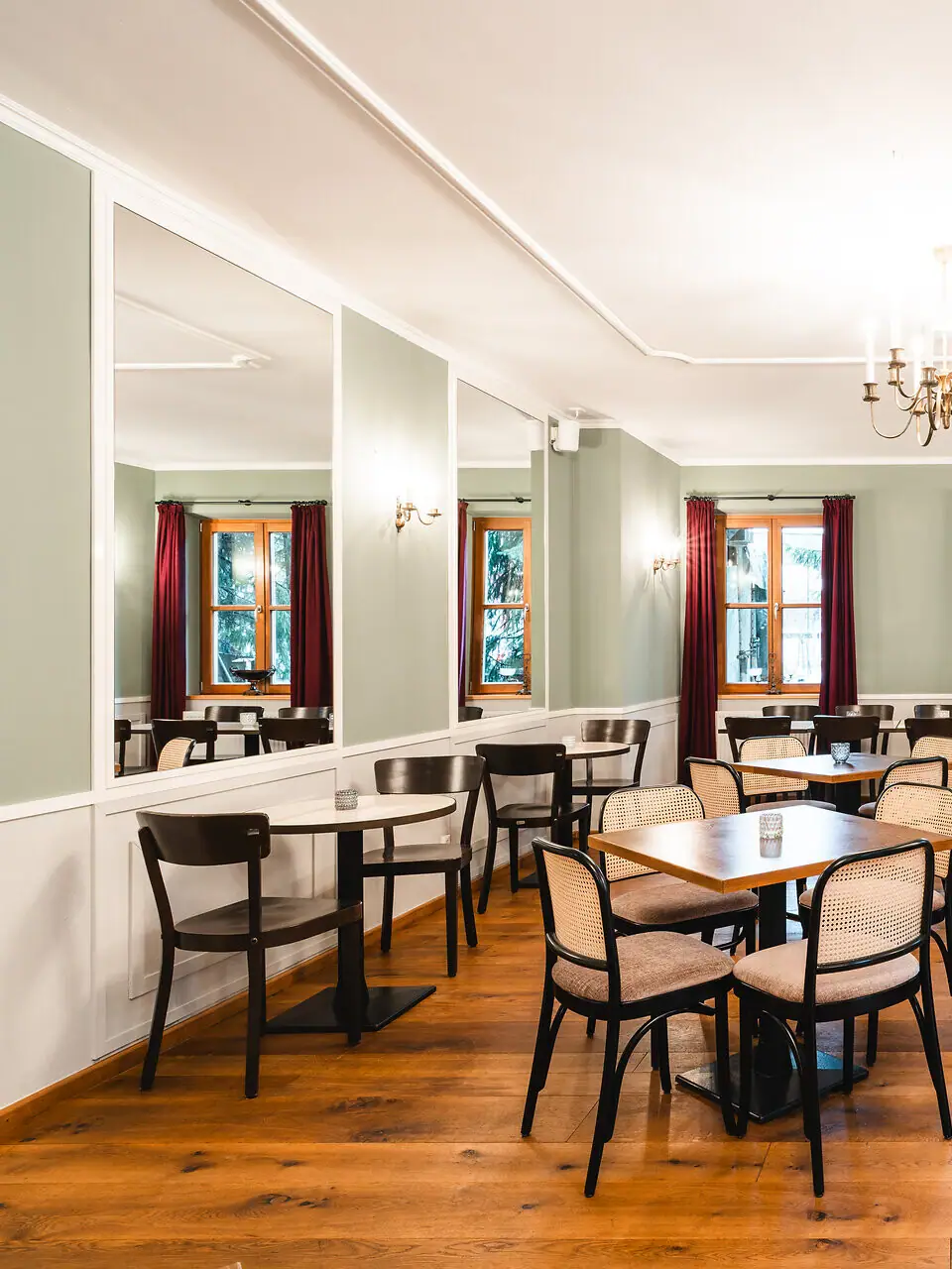 Una stanza luminosa con tavoli e sedie e specchi alle pareti.